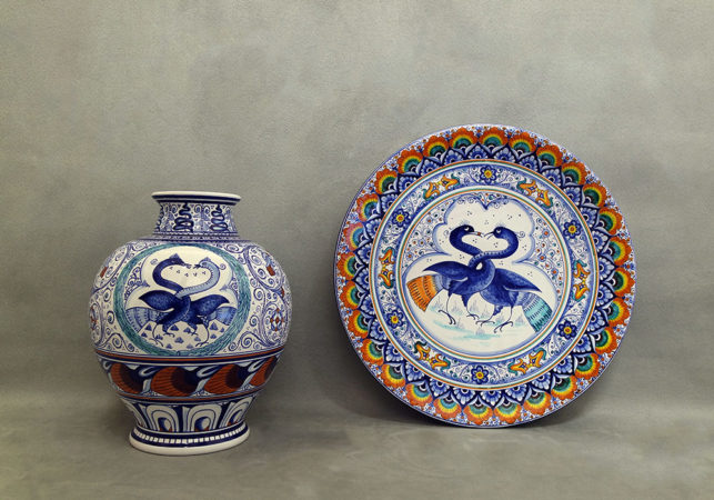 vaso e piatto in maiolica con uccelli dal collo intrecciato