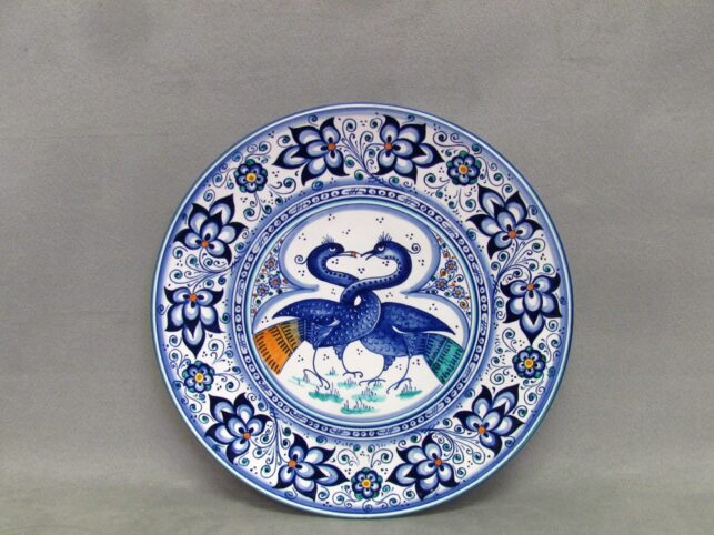 piatto in ceramica con astorri dal collo intrecciato